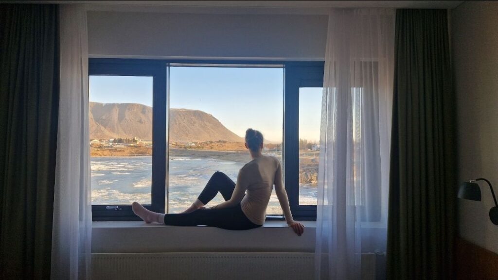 A woman looking out of the window into the peaceful outdoors. Representing releaxation and enhancing dream body affirmations.