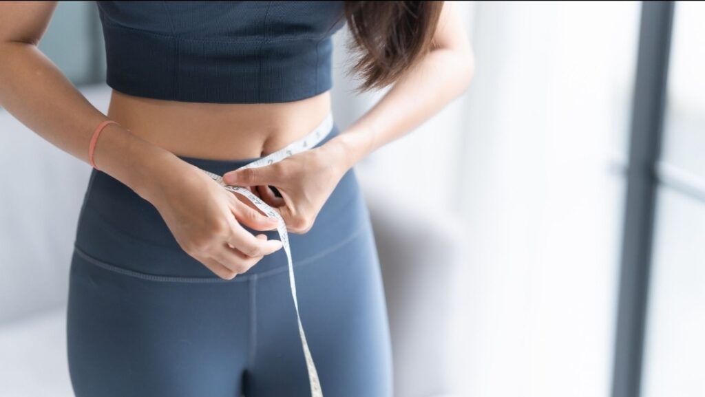 Measuring waist circumference to track fat loss progress during a calorie deficit.