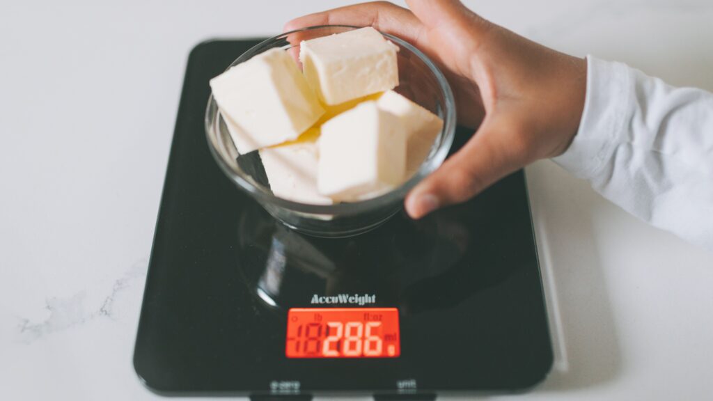 Weighing food on a kitchen scale to track calories during a calorie deficit.